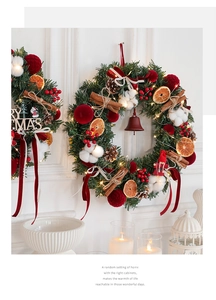 Close-up of red Christmas wreath with velvet balls, pine cones, and warm LED lights