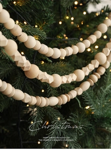 Detail of natural wooden bead garland with geometric shapes hanging on Christmas tree