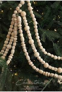 Close-up of natural wood bead garland with geometric shapes hanging on a Christmas tree