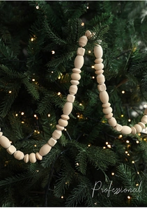 Detail of wooden bead garland with geometric shapes hanging on a decorated Christmas tree