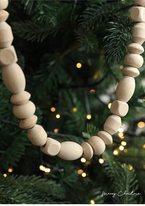 Detail of assorted wooden beads hanging on a Christmas tree with warm festive lights