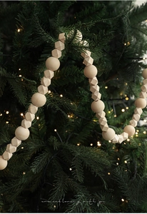 Macro detail of natural wooden bead garland wrapped on a Christmas tree with warm lights