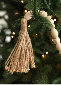 Close-up of natural wood bead garland with jute tassel hanging on Christmas tree branch