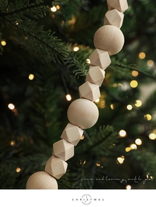 Close-up of geometric and round wooden beads on a festive garland with holiday lights