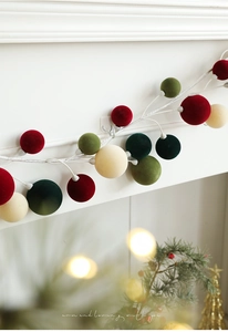 Detailed close-up of velvet Christmas ornaments on a white vine with festive bokeh background