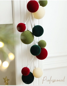 Detail of Christmas velvet ball garland in red green and white for fireplace decor