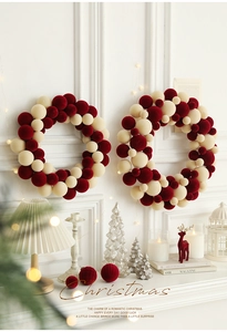 Detail of red and beige velvet ball Christmas wreaths in two sizes on a white wall decor