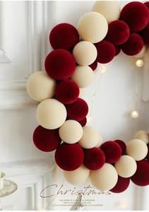 Detailed view of red and beige velvet Christmas ball wreath with warm glowing LED lights