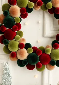 Close-up of colorful flocked velvet Christmas ball wreath with warm glowing LED lights