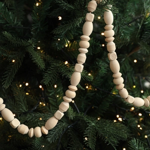 Natural wood bead garland with geometric shapes hanging on a Christmas tree branch
