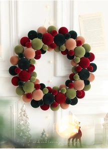 Close-up of a festive Christmas wreath made of colorful flocked balls on a white wall