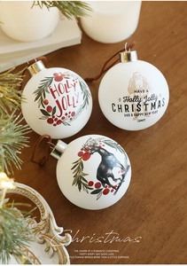 Detalle de bolas de Navidad en vidrio blanco mate con diseños festivos de renos y acebo