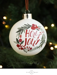 Primer plano de una bola de Navidad de cristal blanco con diseño Holly Jolly