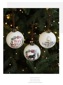 Detalle de bolas de Navidad de 8cm en vidrio blanco con estampados de renos y Papá Noel