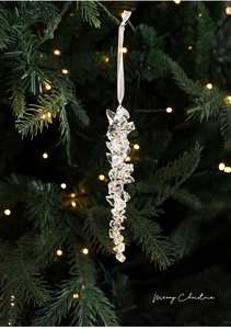 Detail of crystal acrylic icicle ornament hanging on a Christmas tree with warm lights