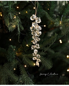 Close-up of clear acrylic berry-shaped pendant hanging on a festive Christmas tree branch