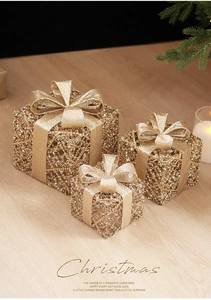 Close-up of three sparkling golden wire mesh Christmas gift boxes with festive glitter bows