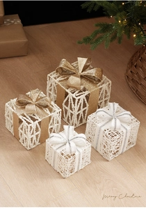 Set of gold and white wire Christmas gift boxes with bows on wooden floor decor