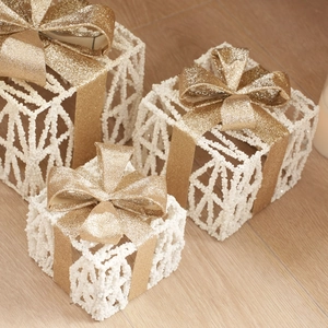 Three-piece set of white rattan gift boxes with gold glitter bows and pine cone decor