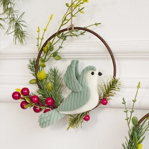 Christmas wreath with plush bird, red berries, and pine needles on a circular frame
