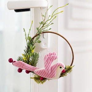 Detail of pink corduroy bird on wooden wreath with pine needles and red berries