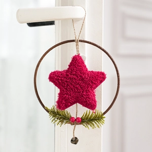 Detail of Christmas wreath with plush star, pine needles, berries and a small bronze bell