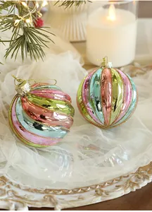 Detail of candy-striped Christmas balls with gold glitter on white mesh with candles