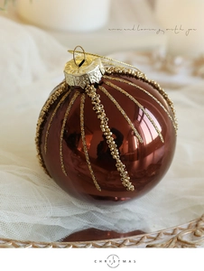 Macro detail of brown Christmas ball ornament with gold glitter stripes and beads