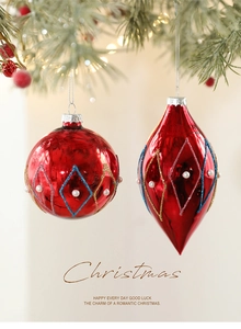 Detail of red glitter Christmas ball ornament with pearls hanging on a tree branch