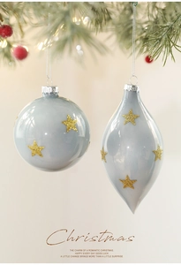 Detail of blue Christmas ornaments with gold glitter stars hanging on a festive pine branch