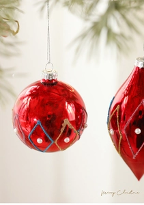 Macro detail of red Christmas ornaments with gold glitter lines and white pearl accents