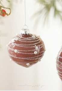 Detailed view of chocolate brown Christmas ball with white pearl spiral and silver cap