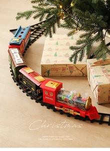 Detail of red electric Christmas train with gear mechanism on track near tree