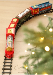 Classic electric Christmas train set with retro red engine on tracks by a festive tree