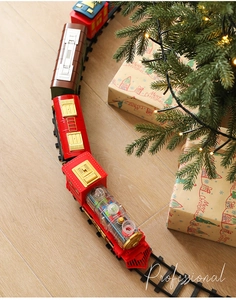 Electric Christmas train set with transparent gears on circular track near a Christmas tree