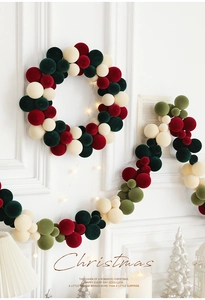 Detail of Christmas wreath with velvet balls and warm LED lights on a white wall