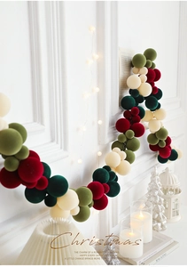 Detail of velvet Christmas balls in red and olive green on a festive wall garland