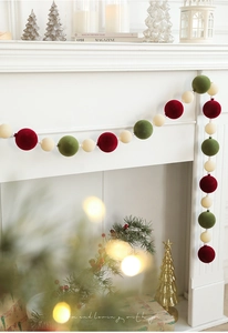 Detail of red and green velvet Christmas ball garland hanging on a fireplace mantel