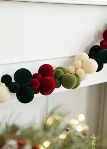 Detail of colorful velvet Christmas ball garland draped on a white fireplace mantel