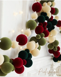 Detail of colorful flocked Christmas ball garland on white mantel with festive lights