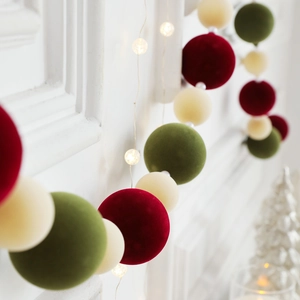 Christmas garland with red green and cream flocked balls and warm LED fairy lights