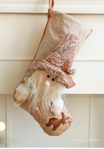 Détail de chaussette de Noël or champagne avec gnome en peluche et motif renne à paillettes