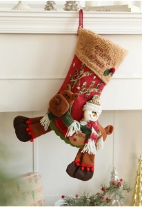Détail de chaussettes de Noël en peluche avec renne 3D et bonhomme de neige sur cheminée