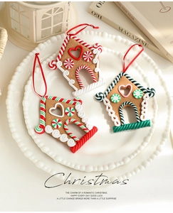 Three gingerbread house Christmas ornaments with candy details on a white ceramic plate