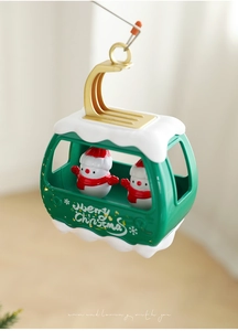 Macro shot of a green Christmas cable car ornament with snowmen and Merry Christmas text