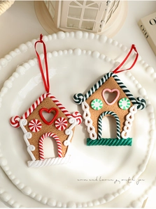 Detailed macro view of festive gingerbread house clay charms with red hanging ribbons