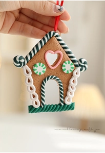 Detailed view of polymer clay gingerbread house ornament with candy edges and a red ribbon