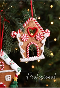 Close-up of a gingerbread house ornament with red ribbons on a Christmas tree branch