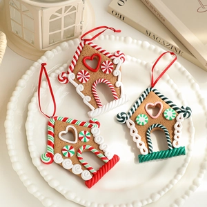 Three gingerbread house Christmas tree ornaments with colorful candy patterns and red ribbons