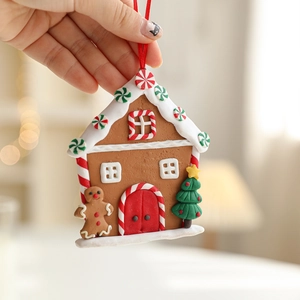 Gingerbread house Christmas ornament with snow-covered roof and red silk hanging ribbon